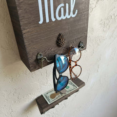 eBun wooden mail holder with sunglasses and money attached to it on a textured wall.